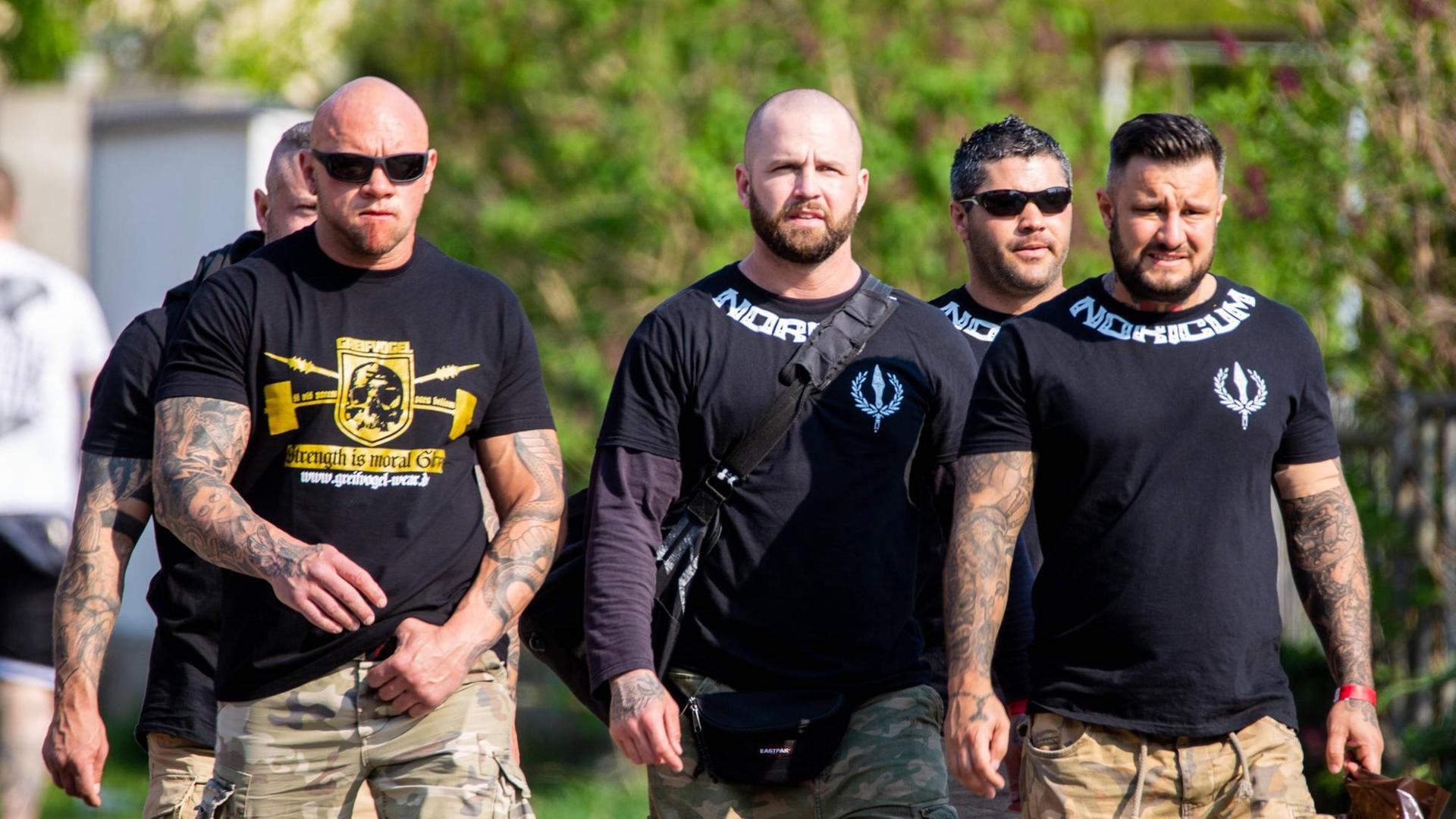 Vier Männer mit durchtrainierten Körpern auf ihren T-Shirts steht "Noricum", der Name ihrer Kampfsportgruppe Vier Männer mit durchtrainierten Körpern auf ihren T-Shirts steht "Noricum", der Name ihrer Kampfsportgruppe
