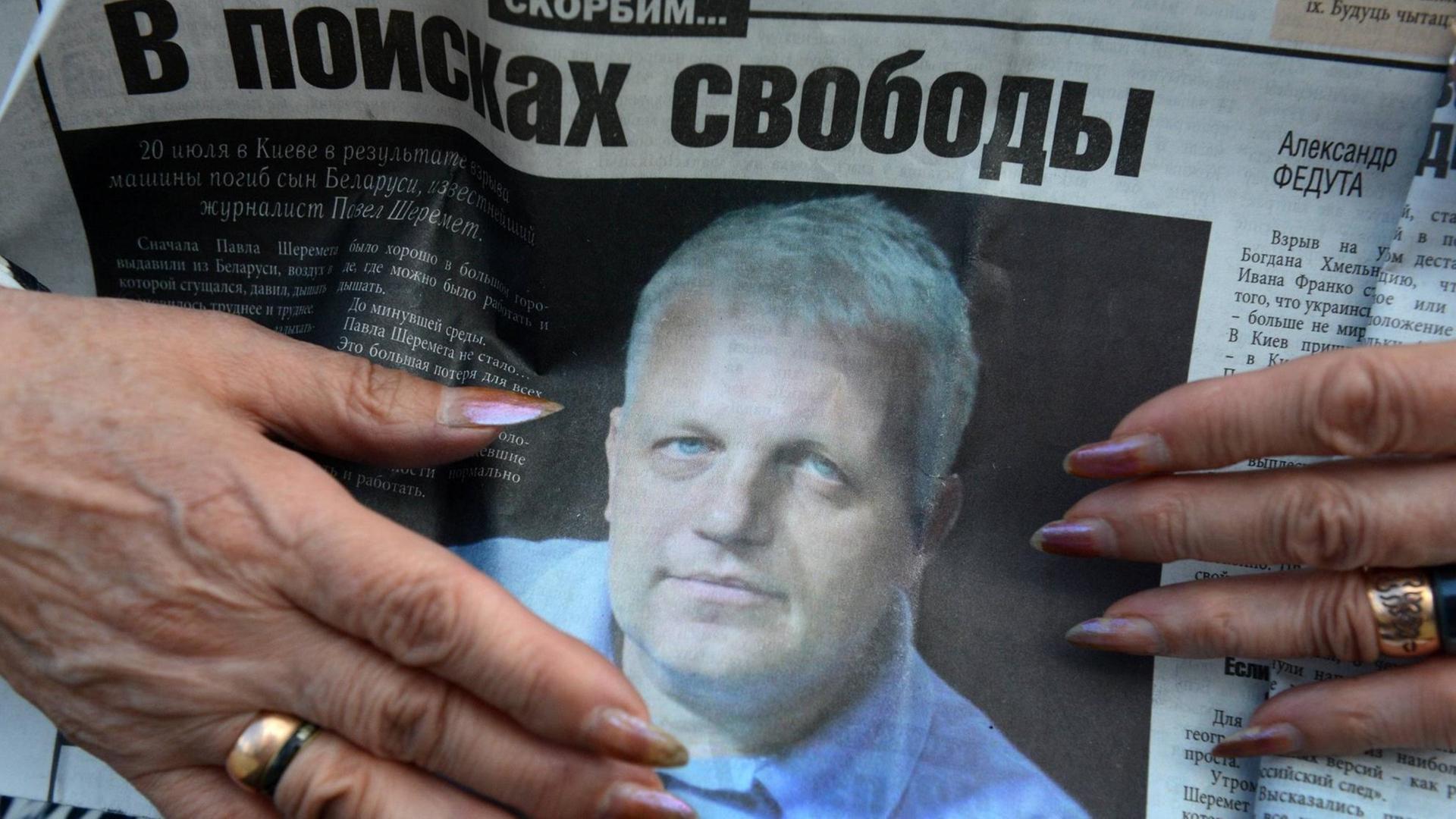 Eine Person hält eine Zeitung mit dem Photo des ermordeten Journalisten Pawel Scheremet während seiner Beerdigung am 23. Juli 2016 auf dem Severnoye Friedhof in Minsk, Weißrussland. Eine Person hält eine Zeitung mit dem Photo des ermordeten Journalisten Pawel Scheremet während seiner Beerdigung am 23. Juli 2016 auf dem Severnoye Friedhof in Minsk, Weißrussland.