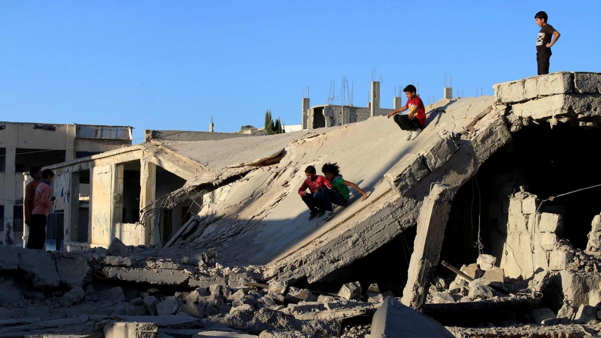 Syrische Kinder spielen in Ruinen.