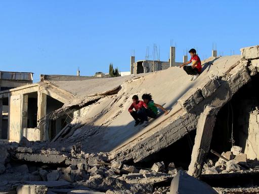 Syrische Kinder spielen in Ruinen.