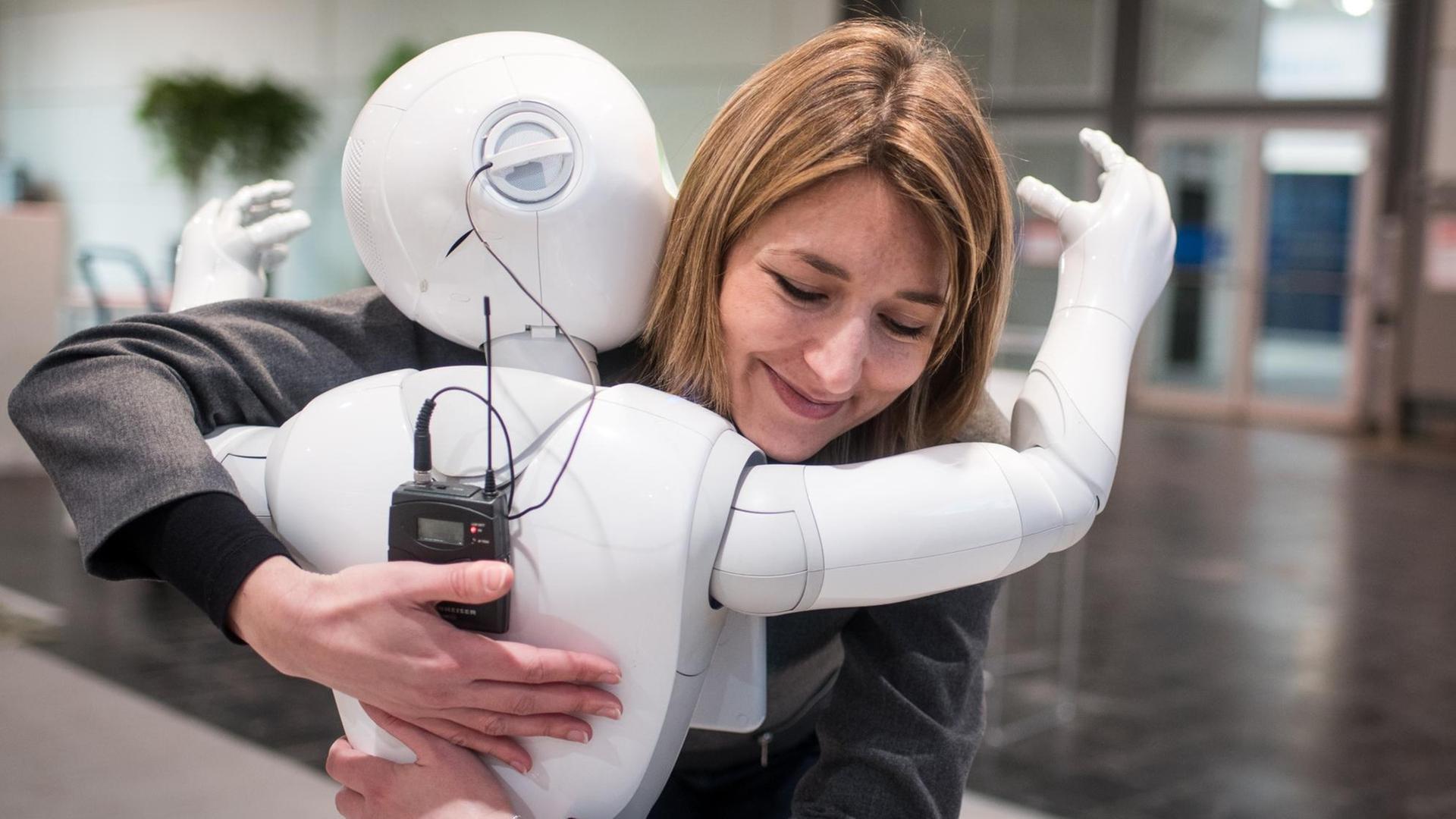 Die Kommunikationsmanagerin von Aldebaran, Aurora Chiquot, umarmt auf der CeBIT Hannover 2016 den humanoiden Roboter "Pepper".