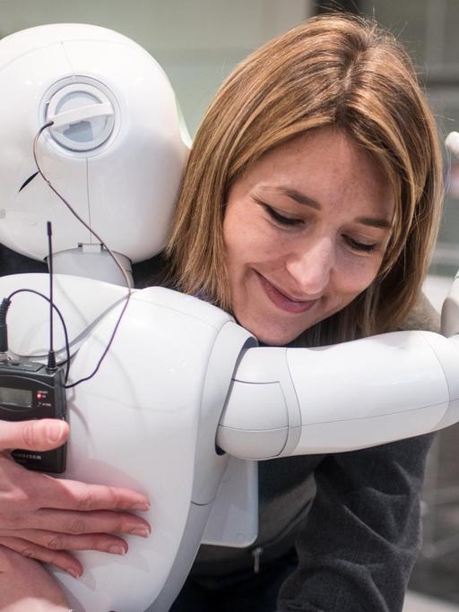 Die Kommunikationsmanagerin von Aldebaran, Aurora Chiquot, umarmt auf der CeBIT Hannover 2016 den humanoiden Roboter "Pepper".