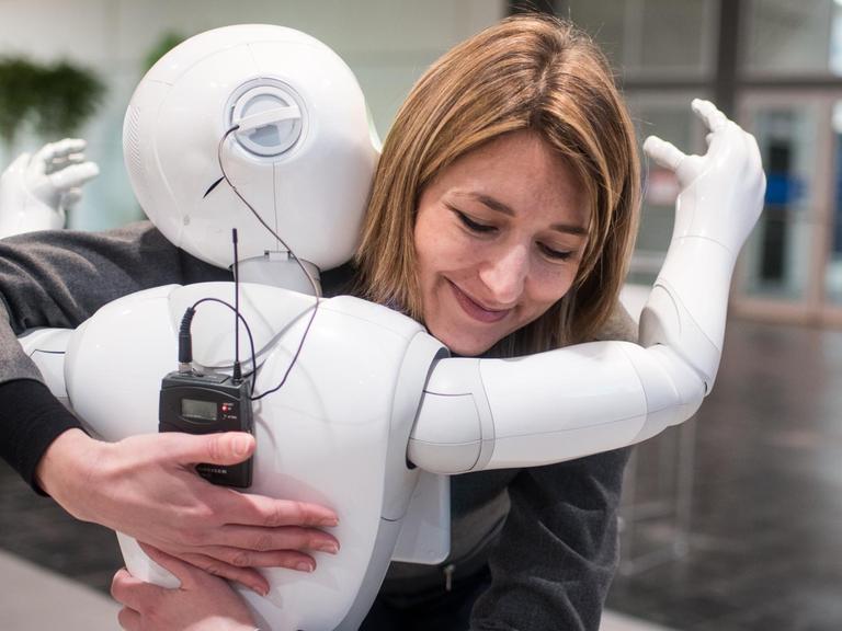 Die Kommunikationsmanagerin von Aldebaran, Aurora Chiquot, umarmt auf der CeBIT Hannover 2016 den humanoiden Roboter "Pepper".