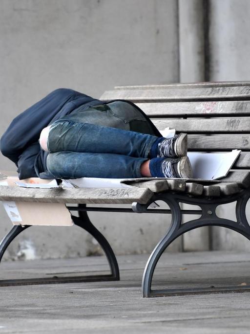 Ein Mann schläft in Berlin auf einer mit Pappkarton ausgelegten Bank im Regierungsviertel.