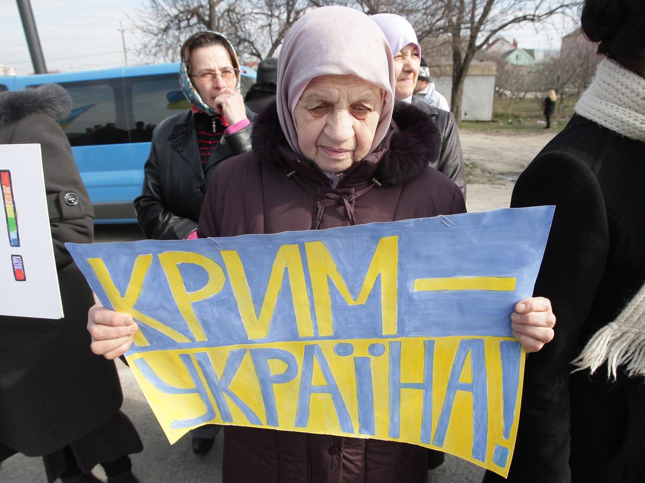 Eine ältere Frau hält ein Poster in den ukrainischen Nationalfarben blau und gelb hoch, auf dem steht: "Krim - Ukraine". Eine ältere Frau hält ein Poster in den ukrainischen Nationalfarben blau und gelb hoch, auf dem steht: "Krim - Ukraine".