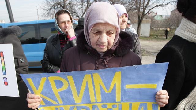 Eine ältere Frau hält ein Poster in den ukrainischen Nationalfarben blau und gelb hoch, auf dem steht: "Krim - Ukraine".