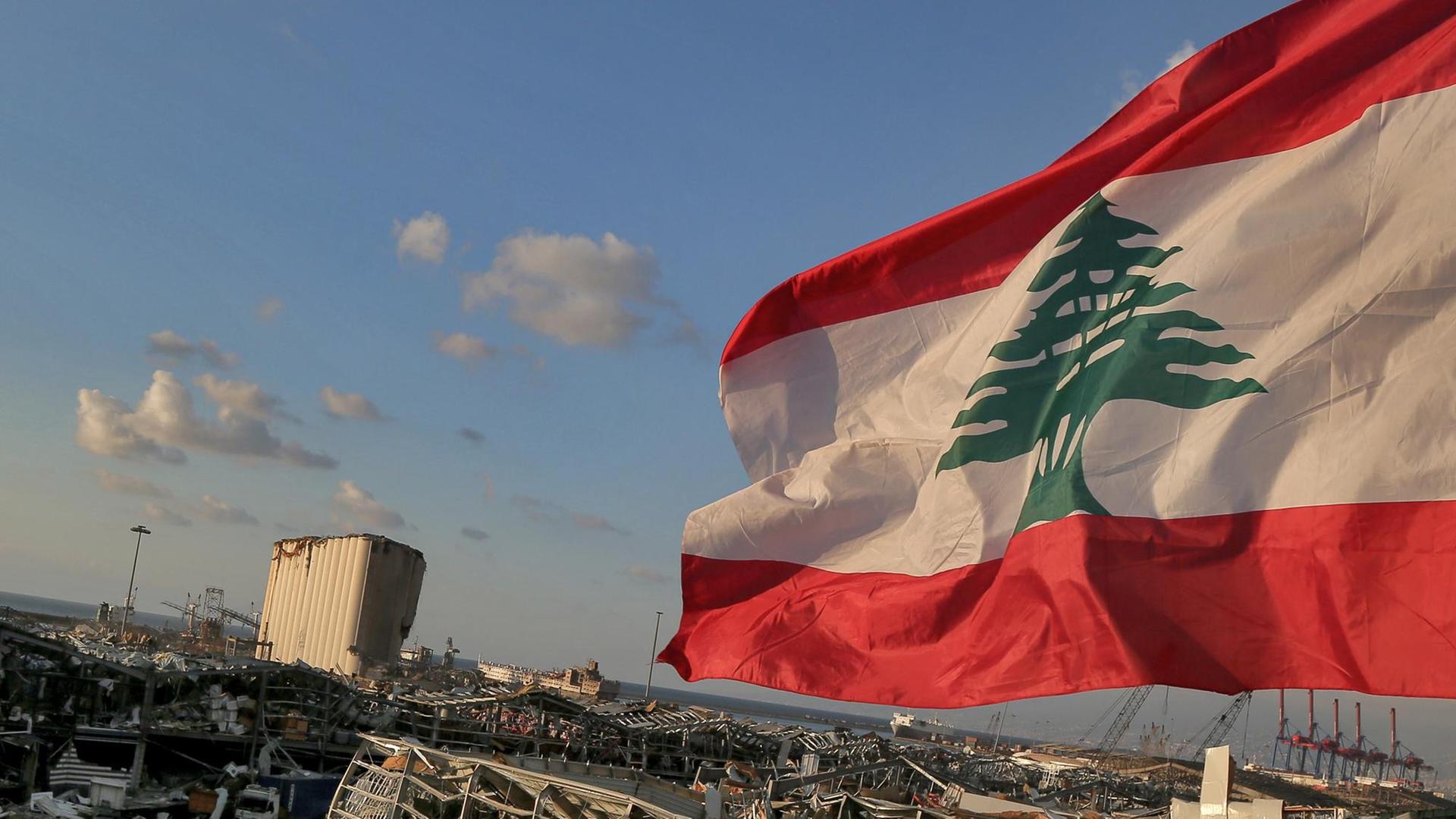 Eine libanesische Flagge weht in der Nähe der Stelle, an der eine massive Explosion den Hafen von Beirut in die Luft sprengte Eine libanesische Flagge weht in der Nähe der Stelle, an der eine massive Explosion den Hafen von Beirut in die Luft sprengte