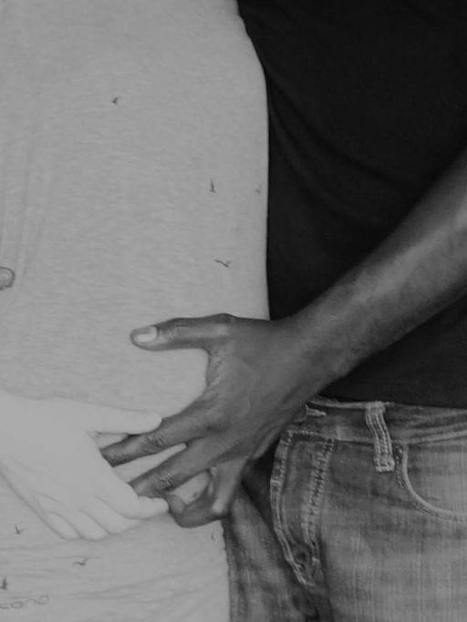 Ein Paar - sie schwanger und weiß, er Schwarz - hält sich in den Armen.