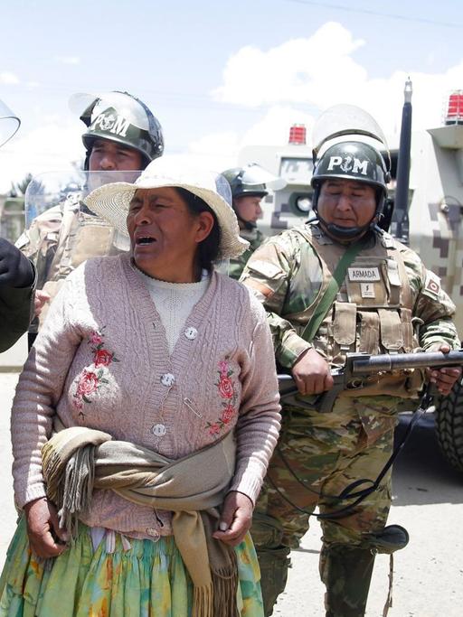 Protest am Eingang der Treibstoffanlage Senkata in der Stadt El Alto. Eine Frau mit verzerrten Gesicht ist zwischen mehreren Soldaten zu sehen.