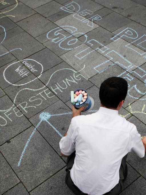 Ein Missionar der Mormonen malt unter anderem "Der Plan Gottes" auf den Boden einer Fußgängerzone.