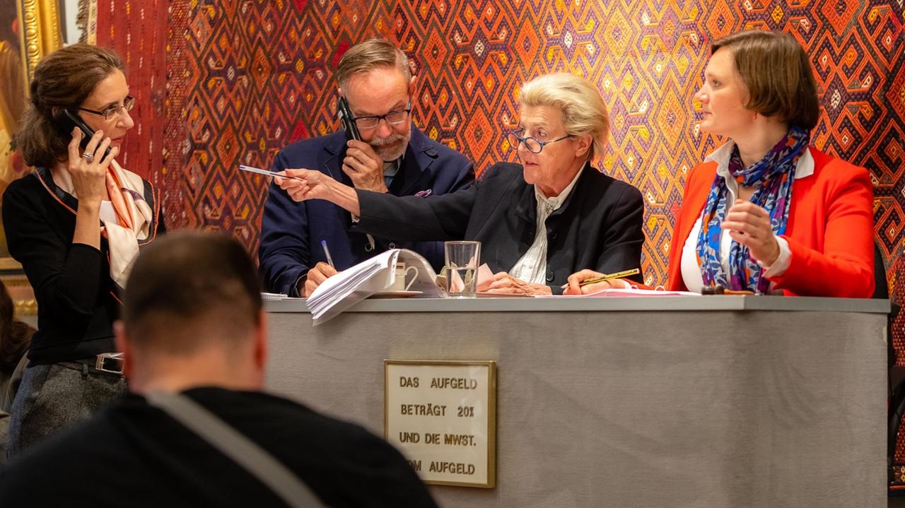 Zwei Frauen und ein Mann stehend an einem Tisch - eine Frau und eine Mann telefonierend. Zwei Frauen und ein Mann stehend an einem Tisch - eine Frau und eine Mann telefonierend.