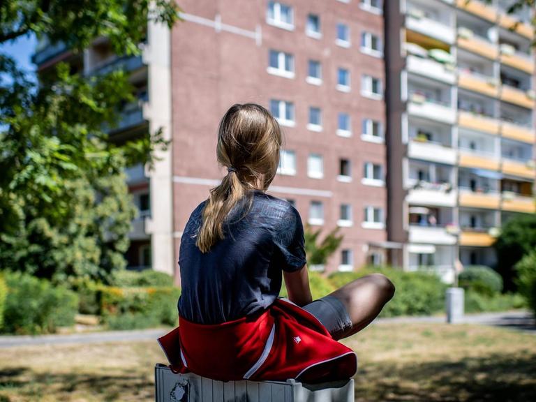 Ein Kind sitzt vor einem Plattenbau in Leipzig-Gruenau. 31. Juli 2020.