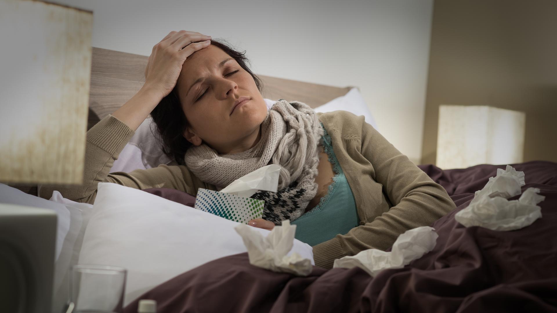 Eine Frau liegt krank im Bett. Eine Frau liegt krank im Bett.