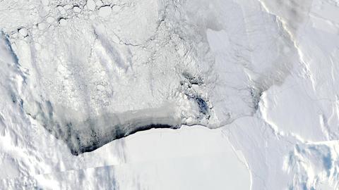 Luftaufnahme der Eisdecke in der Antarktis, an einer Stelle hat sie einen breiten Riss.