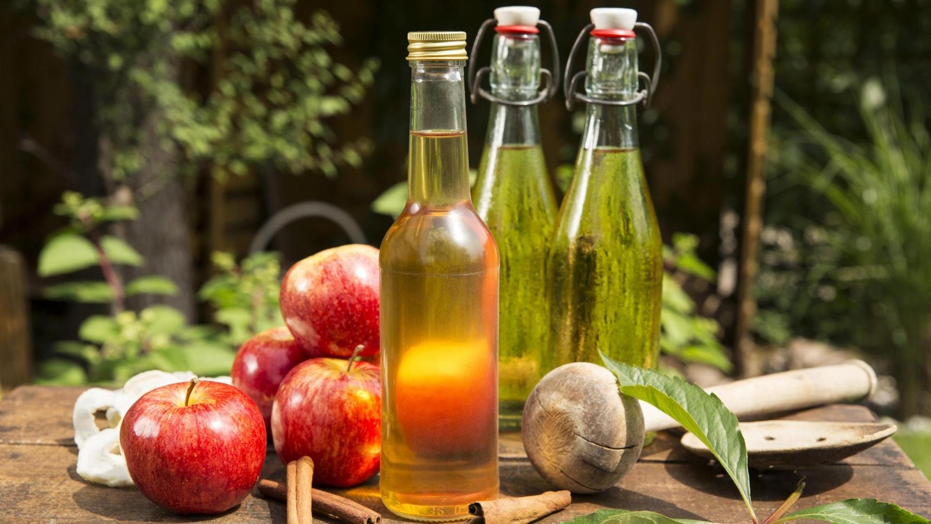Äpfel mit Apfelessig und Apfelsaft auf einer Holzkiste im Garten, Deutschland, Europa. Äpfel mit Apfelessig und Apfelsaft auf einer Holzkiste im Garten, Deutschland, Europa.