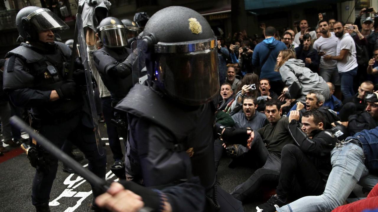 Ein spanischer Nationalpolizist geht mit seinem Schlagstock auf Befürworter des Katalonien-Referendums los, die sich auf die Straße gesetzt haben, am 01.10.2017 in Barcelona (Spanien). Ein spanischer Nationalpolizist geht mit seinem Schlagstock auf Befürworter des Katalonien-Referendums los, die sich auf die Straße gesetzt haben, am 01.10.2017 in Barcelona (Spanien).