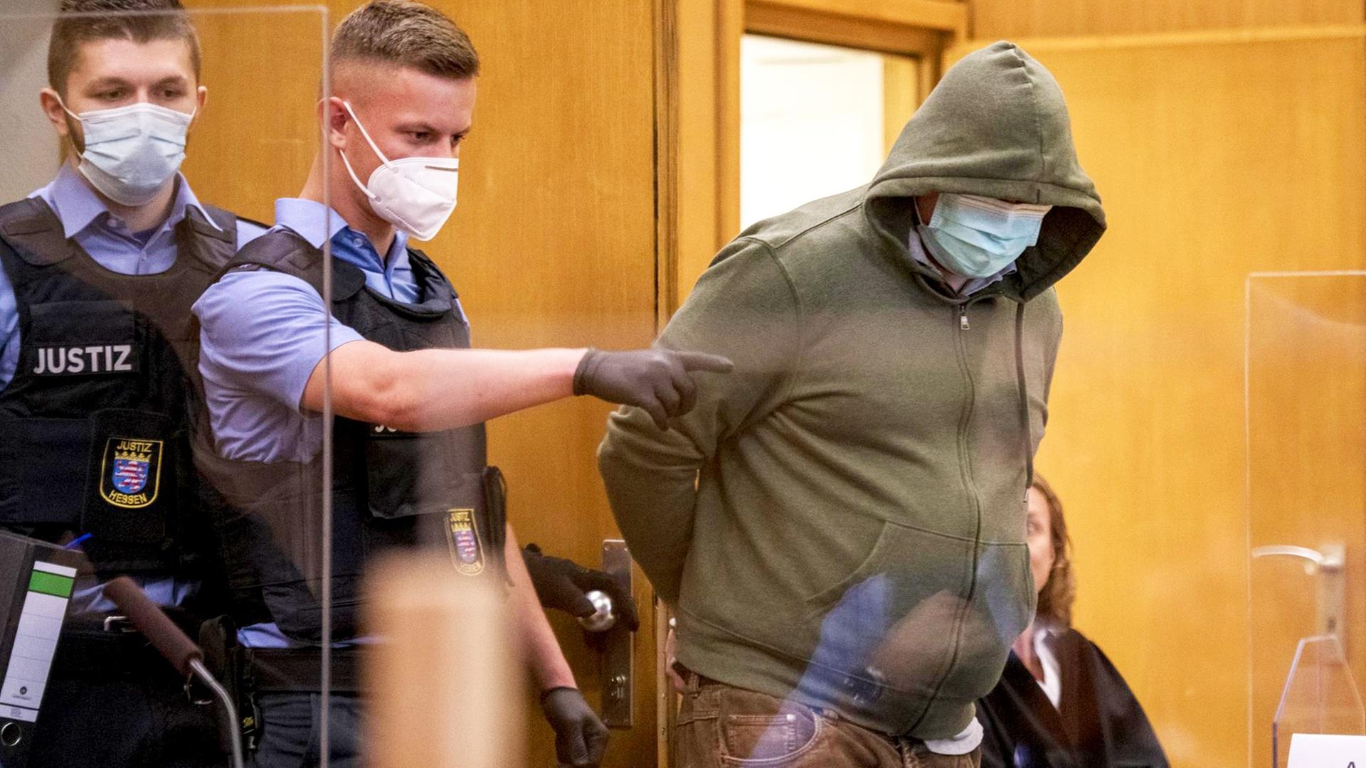 Frankfurt/Main: Markus H. (r), der wegen Beihilfe zum Mord an Politiker Lübcke angeklagt ist, trägt einen Mundschutz, als er am ersten Tag des Prozesses von Polizisten in einen Gerichtssaal des Oberlandesgericht gebracht wird. Frankfurt/Main: Markus H. (r), der wegen Beihilfe zum Mord an Politiker Lübcke angeklagt ist, trägt einen Mundschutz, als er am ersten Tag des Prozesses von Polizisten in einen Gerichtssaal des Oberlandesgericht gebracht wird.