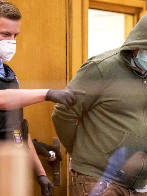 Frankfurt/Main: Markus H. (r), der wegen Beihilfe zum Mord an Politiker Lübcke angeklagt ist, trägt einen Mundschutz, als er am ersten Tag des Prozesses von Polizisten in einen Gerichtssaal des Oberlandesgericht gebracht wird.