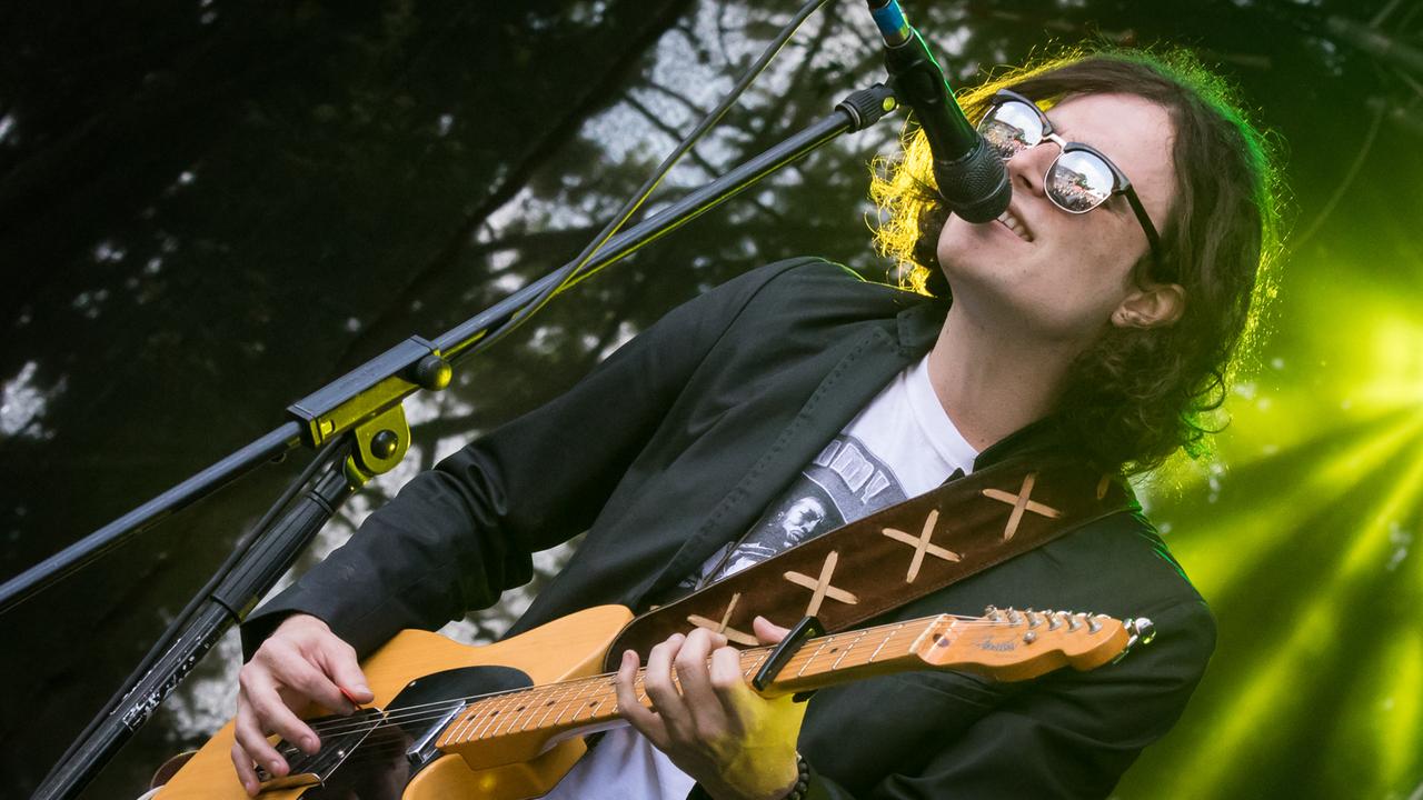 Ein Mann mit schwarzen Haaren und Sonnenbrille spielt Gitarre. Ein Mann mit schwarzen Haaren und Sonnenbrille spielt Gitarre.
