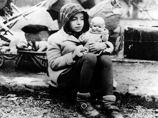 Ein Mädchen aus einem Flüchtlingstreck mit ihrer Puppe im Arm in den Wirren der Nachkriegszeit.