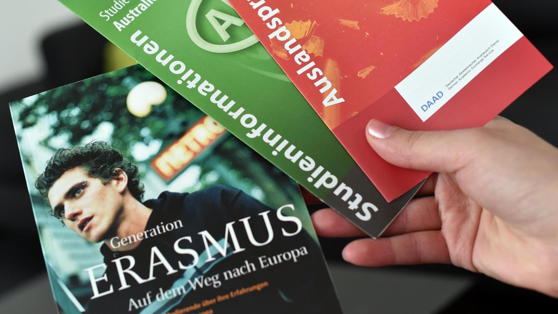 Eine Studentin hält ein Buch über das Erasmus-Programm und Informationsbroschüren über Auslandspraktika in den Händen