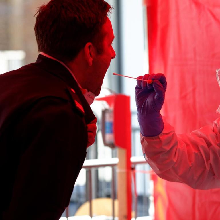 Einem Mitarbeiter der Berufsfeuerwehr Köln wird im dritten Infektionsschutzzentrum der Stadt Köln mit einem Stäbchen ein Abstrich für einen Test auf den Coronavirus entnommen. 
