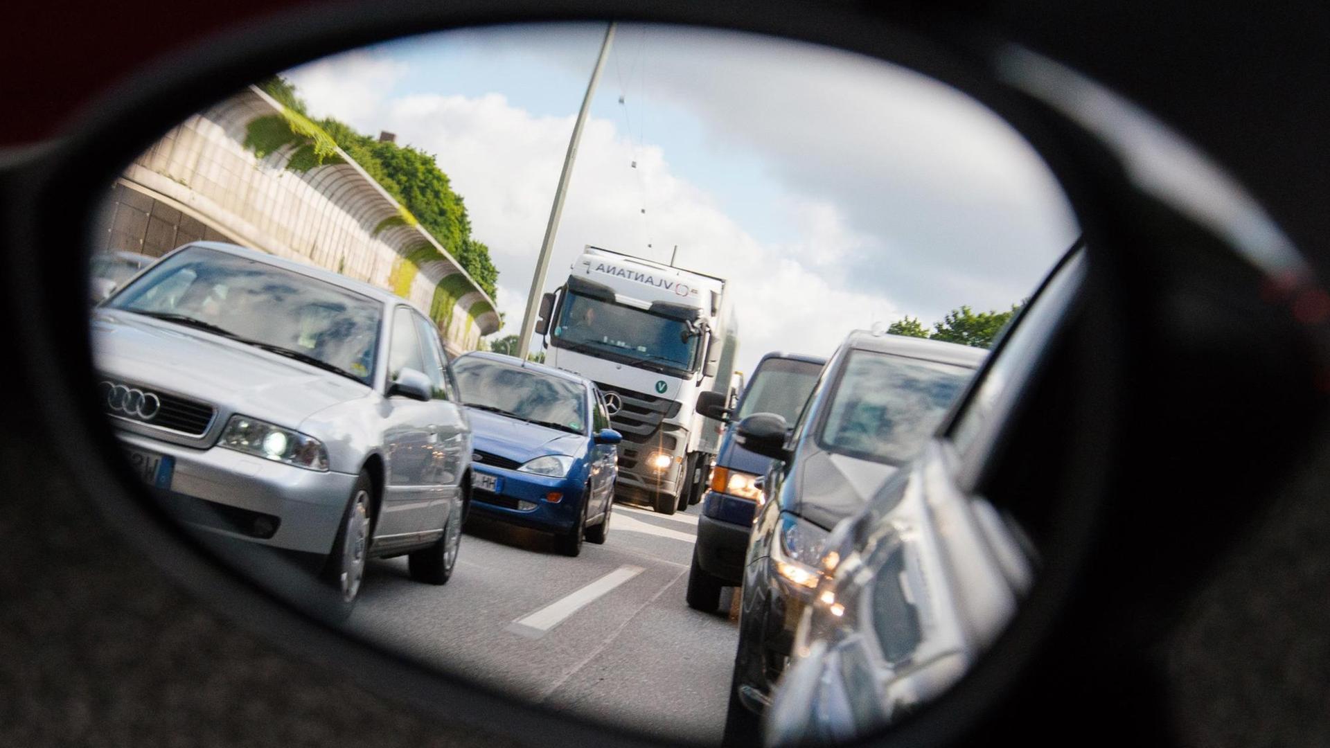 Autos und Lastwagen stehen am 20.06.2015 in Hamburg auf der Autobahn 7 bei Stellingen im Stau und sind dabei durch einen Rückspiegel zu sehen. Autos und Lastwagen stehen am 20.06.2015 in Hamburg auf der Autobahn 7 bei Stellingen im Stau und sind dabei durch einen Rückspiegel zu sehen.