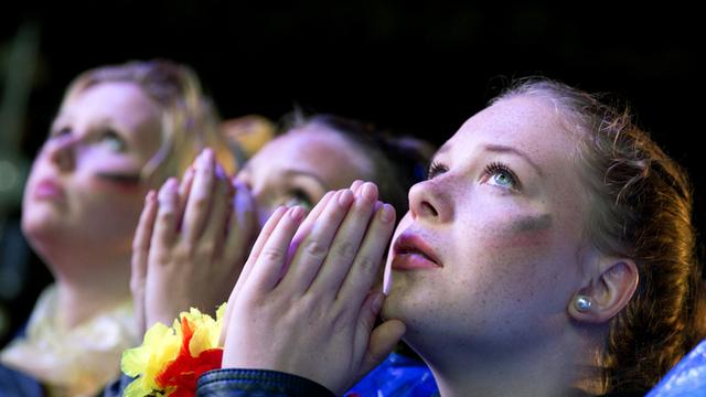 Fans stehen beim "Public Viewing" am Brandenburger Tor in Berlin und sehen sich das WM-Achtelfinale zwischen Deutschland und Algerien in Brasilien an.