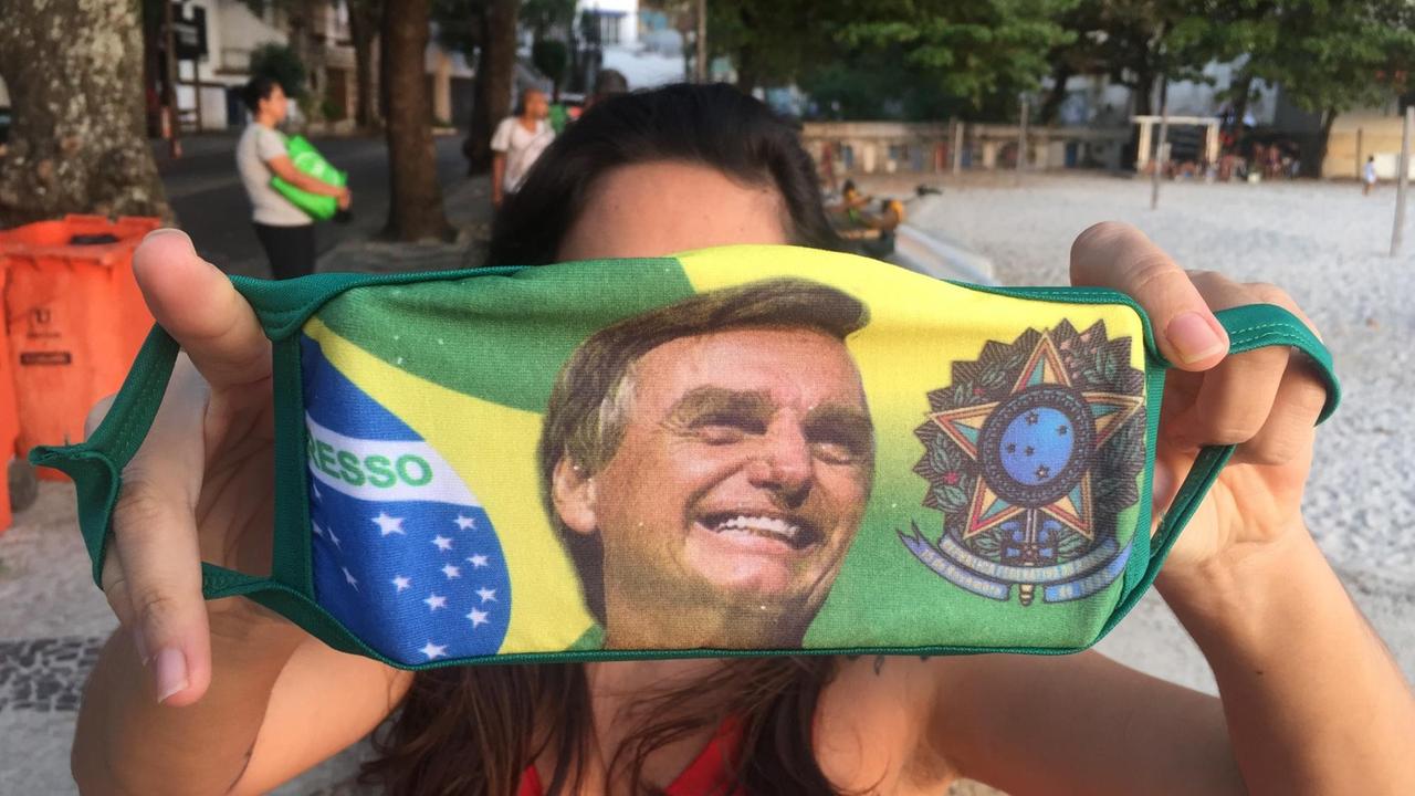 Eine Frau in Rio de Janeiro hält ihre Bolsonaro-Maske in die Kamera. Eine Frau in Rio de Janeiro hält ihre Bolsonaro-Maske in die Kamera.