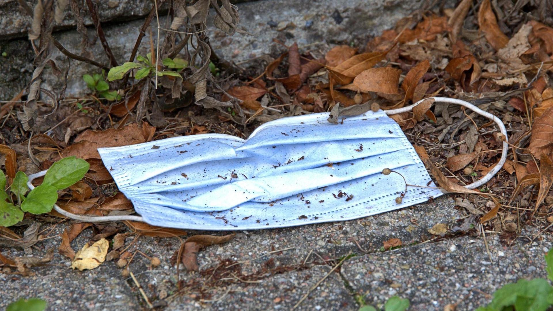 Eine achtlos weggeworfene, benutzte Mund- und Nasenschutz-Maske auf einem gepflasterten Weg. Eine achtlos weggeworfene, benutzte Mund- und Nasenschutz-Maske auf einem gepflasterten Weg.