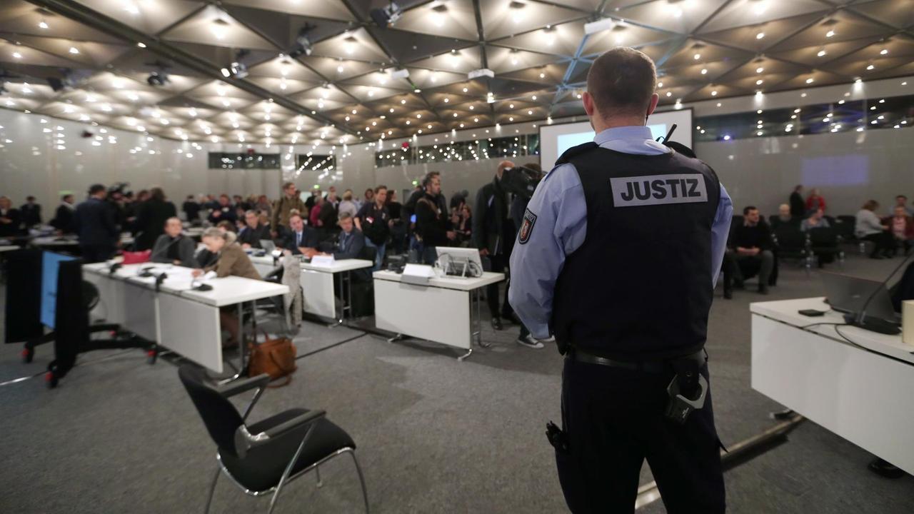 Ein Justizbeamter steht am 08.12.2017 in Düsseldorf (Nordrhein-Westfalen) im Prozesssaal beim Auftakt des Loveparade-Strafprozesses. Das Landgericht Duisburg hat auf dem Gelände der Messe Düsseldorf einen Saal im Kongresszentrum gemietet. Bis Ende 2018 sind zunächst 111 Verhandlungstage eingeplant. Bei der Loveparade am 24. Juli 2010 in Duisburg waren in einem Gedränge 21 Menschen erdrückt und mehr als 650 verletzt worden. Foto: Ina Fassbender/dpa/Pool | Verwendung weltweit Ein Justizbeamter steht am 08.12.2017 in Düsseldorf (Nordrhein-Westfalen) im Prozesssaal beim Auftakt des Loveparade-Strafprozesses. Das Landgericht Duisburg hat auf dem Gelände der Messe Düsseldorf einen Saal im Kongresszentrum gemietet. Bis Ende 2018 sind zunächst 111 Verhandlungstage eingeplant. Bei der Loveparade am 24. Juli 2010 in Duisburg waren in einem Gedränge 21 Menschen erdrückt und mehr als 650 verletzt worden. Foto: Ina Fassbender/dpa/Pool | Verwendung weltweit