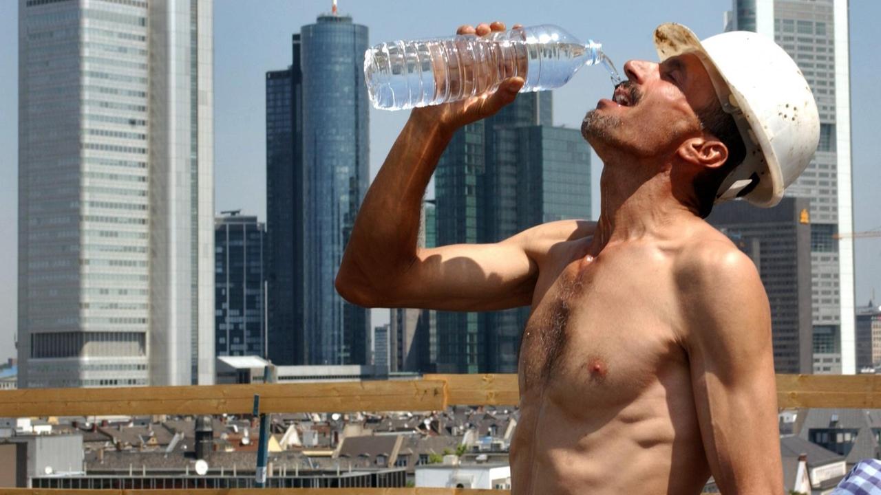 Bei sommerlicher Hitze erfrischt sich ein Bauarbeiter am 11.7.2003 auf einer Baustelle vor der Frankfurter Skyline mit einem Schluck Wasser. Bei Sonne und Temperaturen um 25 Grad ist ein Arbeitsplatz im Freien auch nicht immer ideal... | Verwendung weltweit