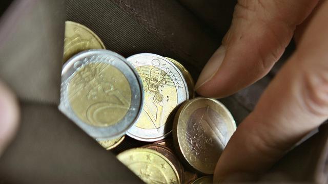 Eine Frau sucht in Köln in ihrem Portemonnaie nach Euro-Münzen.