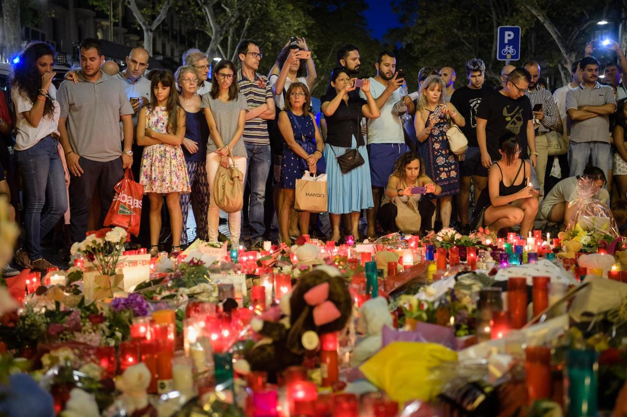 Zahlreiche Menschen blicken am 19.08.2017 auf niedergelegte Kerzen auf der Flaniermeile Las Ramblas in Barcelona (Spanien).