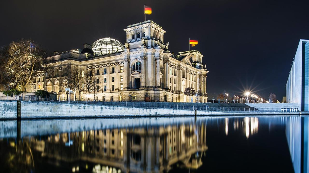 Der Reichstag spiegelt sich am 07.02.2016 in Berlin am frühen Abend bei der Langzeitbelichtung im Wasser der Spree.