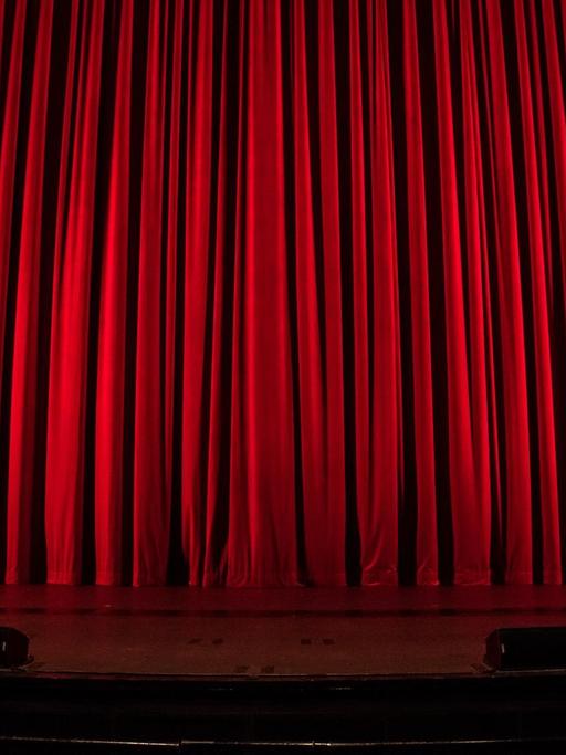 Ein Theater in dem der rote Vorhang zugezogen ist.