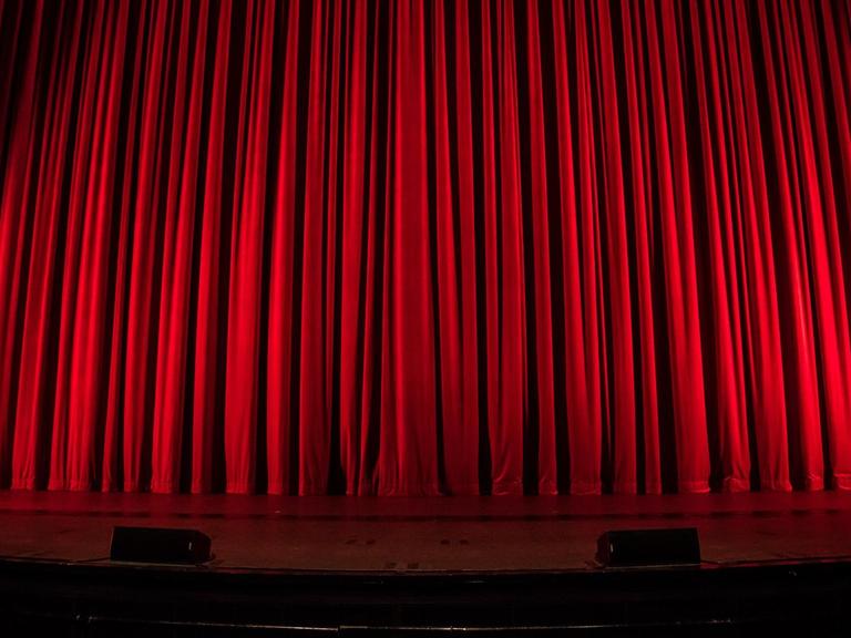 Ein Theater in dem der rote Vorhang zugezogen ist.
