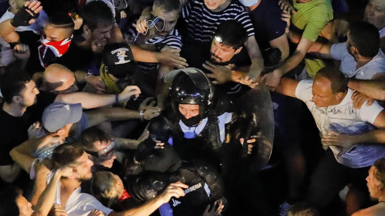 Demonstrationsteilnehmer haben einen gestürzten Polizisten vor dem Regierungssitz der rumänsichen Hauptstadt eingekreist. 
