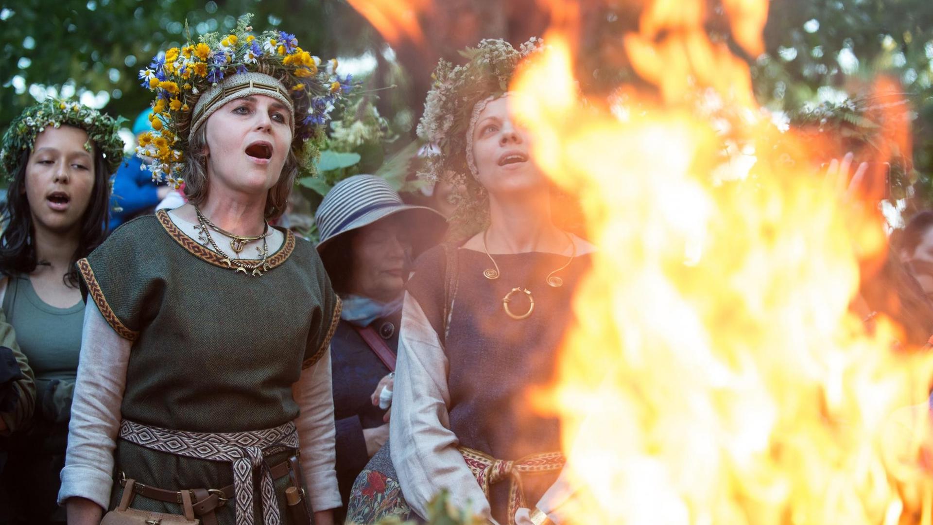 Frauen bei der Feuerzeremonie beim Rasos Festival. Sie tragen Blumenkränze und singen. Frauen bei der Feuerzeremonie beim Rasos Festival. Sie tragen Blumenkränze und singen.