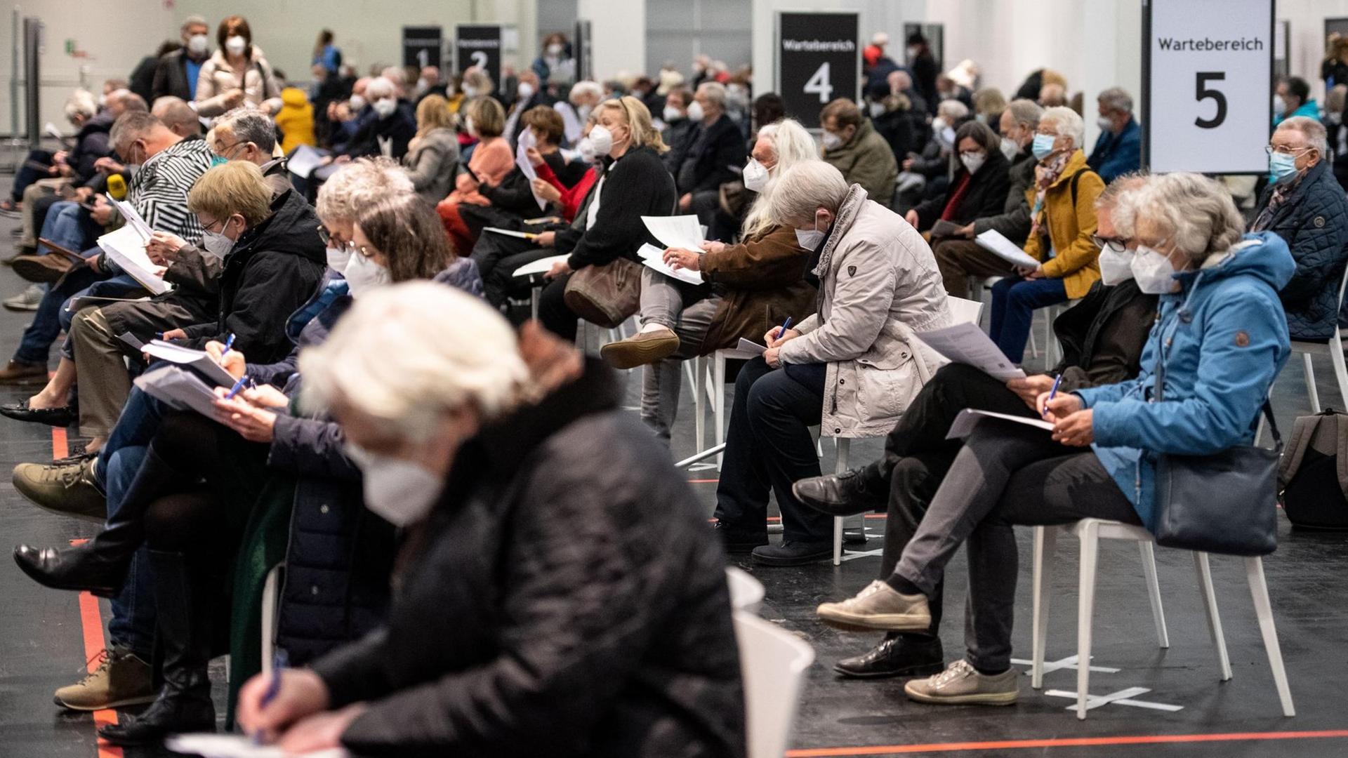 Viele Menschen warten mit Mund-Nasen-Bedeckung in einem Impfzentrum in Nordrhein-Westfalen. Viele Menschen warten mit Mund-Nasen-Bedeckung in einem Impfzentrum in Nordrhein-Westfalen.