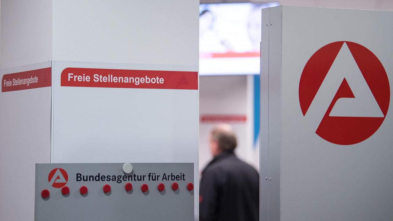 Ein Mann steht hinter einer Stellwand für Stellenangebote. Ein Mann steht hinter einer Stellwand für Stellenangebote.