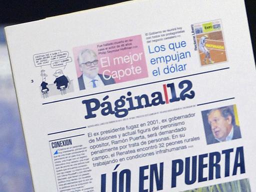 Argentine President Cristina Fernandez de Kirchner shows the front page of a newspaper as she announces rises in basic pensions at the Government Palace in Buenos Aires on February 4, 2014.