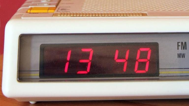 Ein digitaler Radiowecker und ein analoger Wecker auf einem Nachttisch Ein digitaler Radiowecker und ein analoger Wecker auf einem Nachttisch