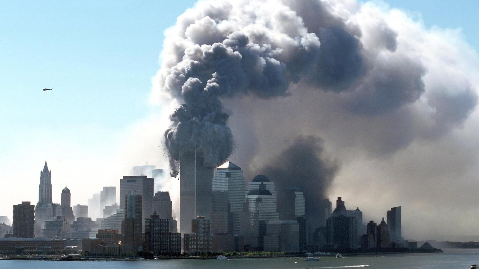 Dicker schwarzer Rauch tritt am 11.9.2001 aus den brennenden Türmen des World Trade Center. Wrack- und Gebäudeteile fliegen auf die Straße. Kurz zuvor waren zwei Flugzeuge hintereinander in die beiden Türme gerast. Dicker schwarzer Rauch tritt am 11.9.2001 aus den brennenden Türmen des World Trade Center. Wrack- und Gebäudeteile fliegen auf die Straße. Kurz zuvor waren zwei Flugzeuge hintereinander in die beiden Türme gerast.