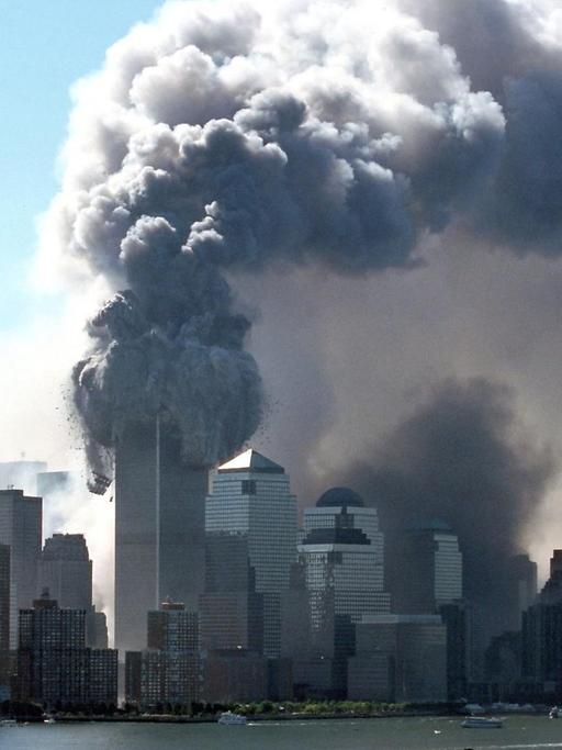 Dicker schwarzer Rauch tritt am 11.9.2001 aus den brennenden Türmen des World Trade Center. Wrack- und Gebäudeteile fliegen auf die Straße. Kurz zuvor waren zwei Flugzeuge hintereinander in die beiden Türme gerast.