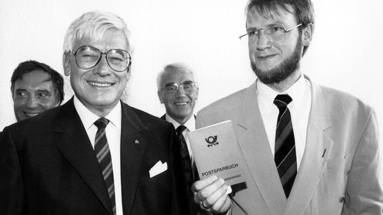 Die beiden deutschen Postminister Christian Schwarz-Schilling (links) und Emil Schnell (DDR) geben am 17.05.1990 bei der Eröffnung der ersten Postbank-Filiale am Alexanderplatz in Berlin die ersten Postsparbücher persönlich aus Die beiden deutschen Postminister Christian Schwarz-Schilling (links) und Emil Schnell (DDR) geben am 17.05.1990 bei der Eröffnung der ersten Postbank-Filiale am Alexanderplatz in Berlin die ersten Postsparbücher persönlich aus