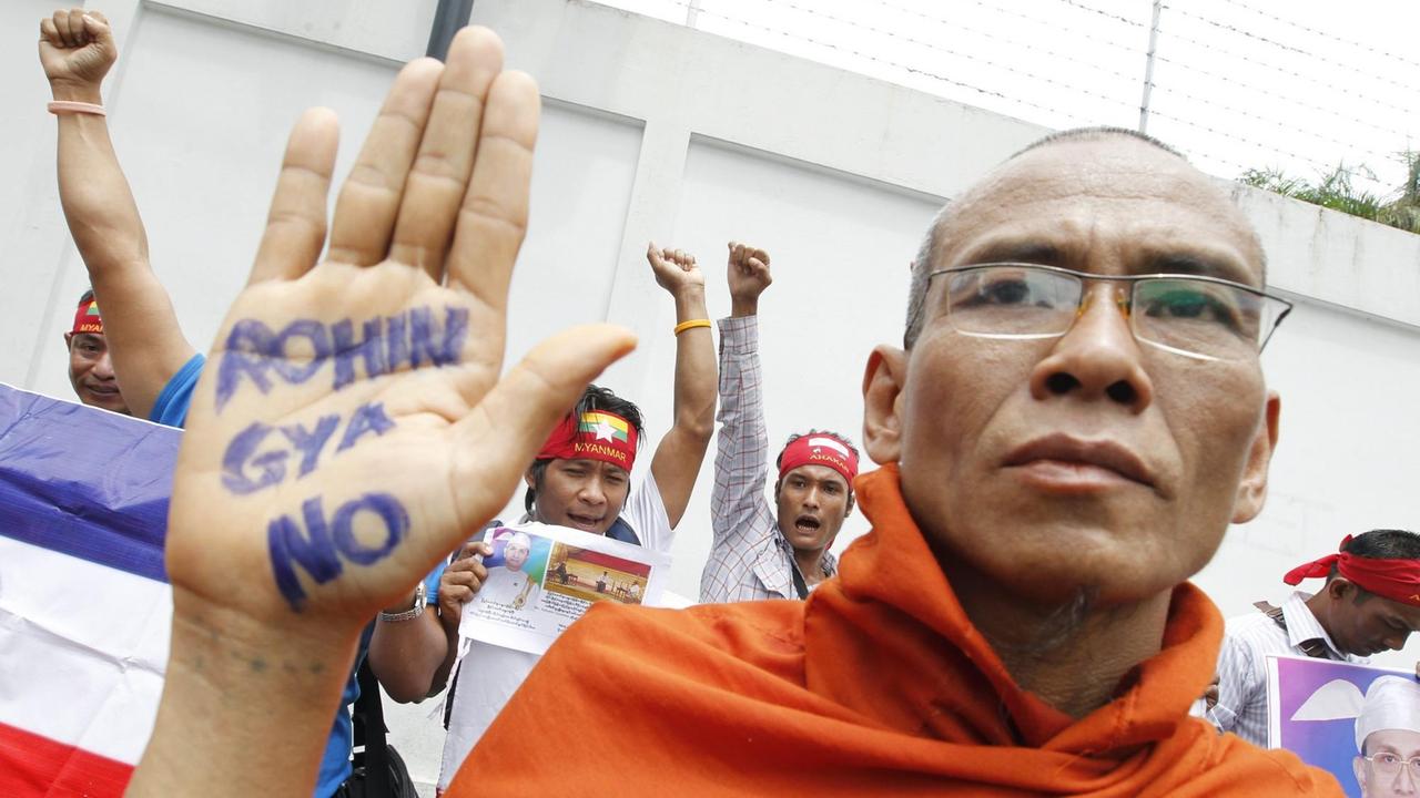 Ein buddhistischer Mönch hält seine Hand hoch, auf der Handfläche steht geschrieben: Rohingya No. Ein buddhistischer Mönch hält seine Hand hoch, auf der Handfläche steht geschrieben: Rohingya No.