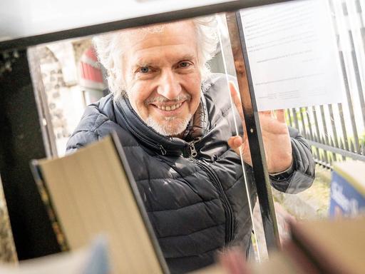 Frank Schätzing stellt sein Buch "Die Tyrannei des Schmetterlings" in einen öffentlichen Bücherschrank am Rheinauhafen in Köln.