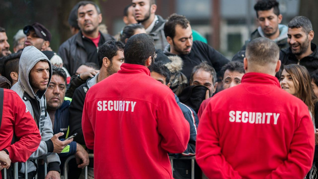 Mitarbeiter einer Sicherheitsfirma organisieren den Einlass von Flüchtlingen am 05.10.2015 in Berlin vor dem Landesamt für Gesundheit und Soziales (LAGESO). 