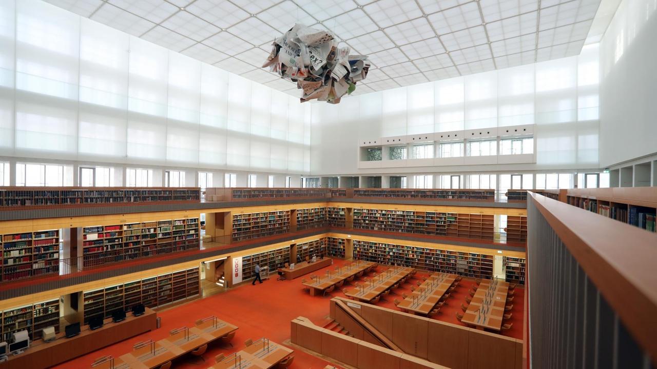 Blick in den neuen und großen Lesesaal der Staatsbibliothek zu Berlin. Die Farben des Bodens und des Mobiliars sind in gelb-rot gehalten.
